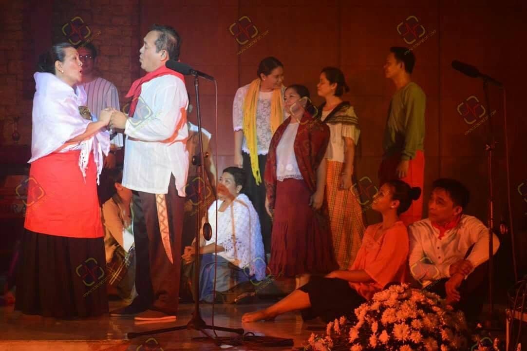 Performers onstage in a dramatic scene supported by warm theatrical lighting